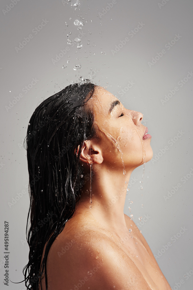 What a great way to start the day. Studio shot of a young woman enjoying a shower against a gray background. What a great way to start the day. Studio shot of a young woman enjoying a shower against a gray background.