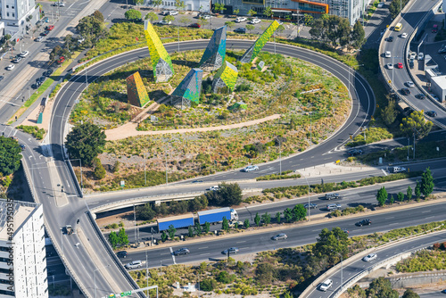 Looking down on a busy freeway with off and on ramps encircling a modern metal sculpture