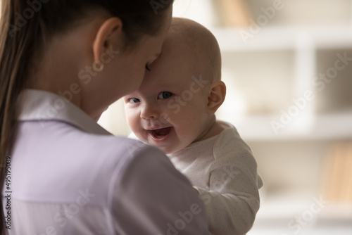 Head shot close up affectionate young mother holding adorable cute newborn baby son daughter, expressing sincere loving feelings, enjoying sweet tender moment together at home, devotion concept.