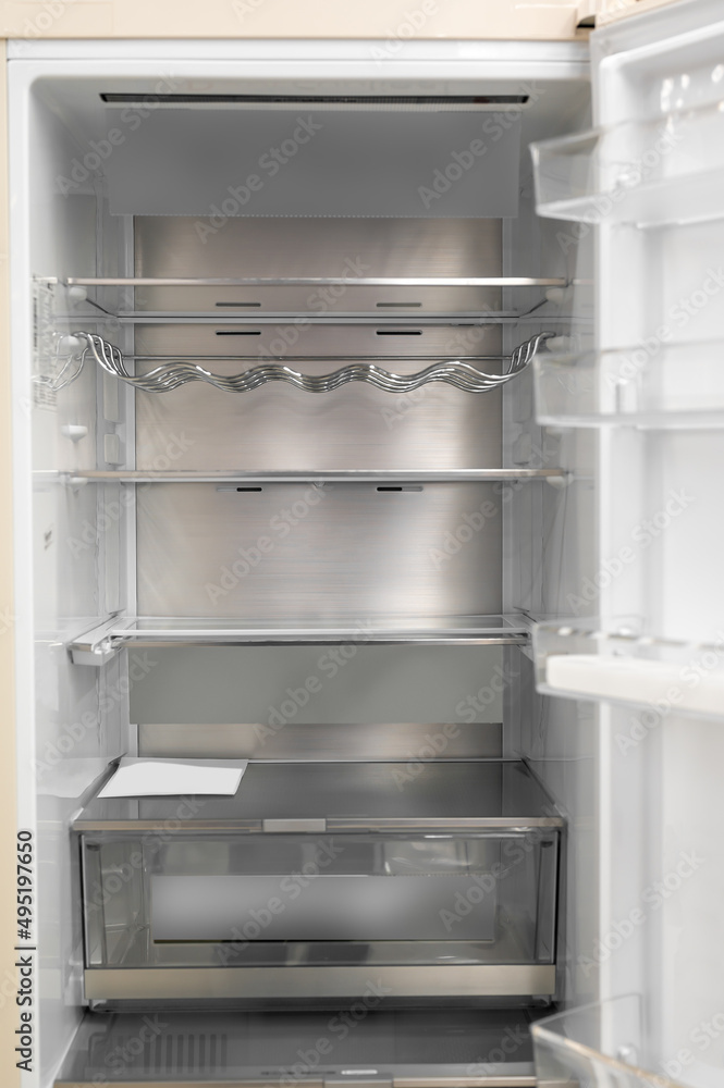 Fototapeta premium Opened empty refrigerator. Refrigerator open empty fridge inside interior. close up on empty fridge with door open. New clean refrigerator.