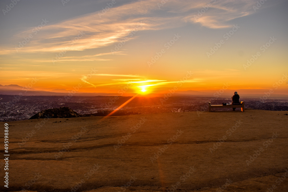 Fototapeta premium Person watching sunrise sitting on bench