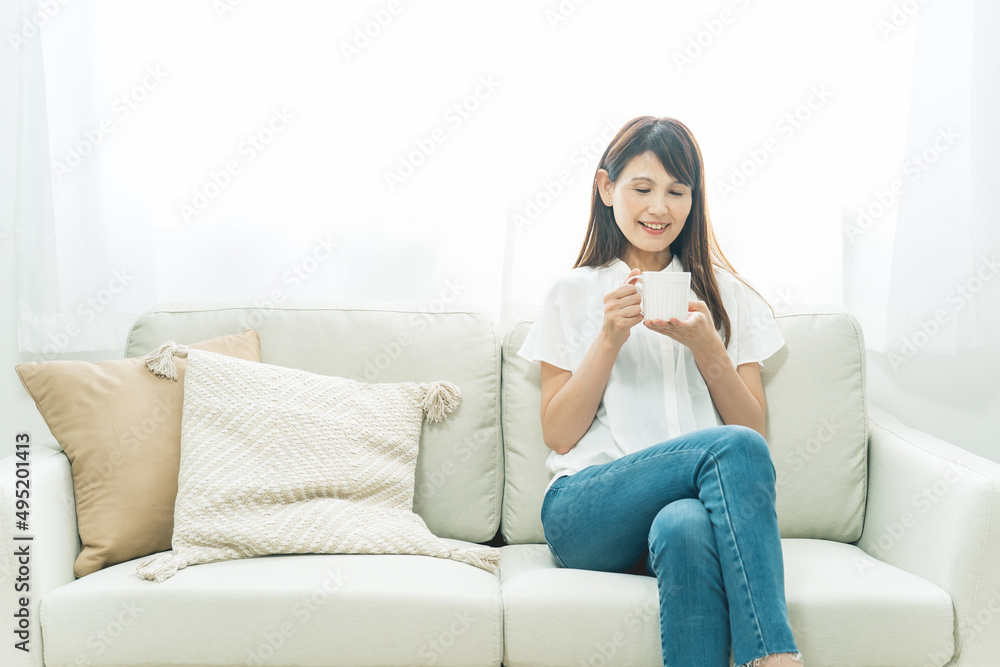 ソファに座る中高年女性(飲み物)
ソファに座る中高年女性(飲み物)