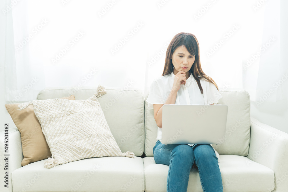 ソファに座る中高年女性(困る)
ソファに座る中高年女性(困る)