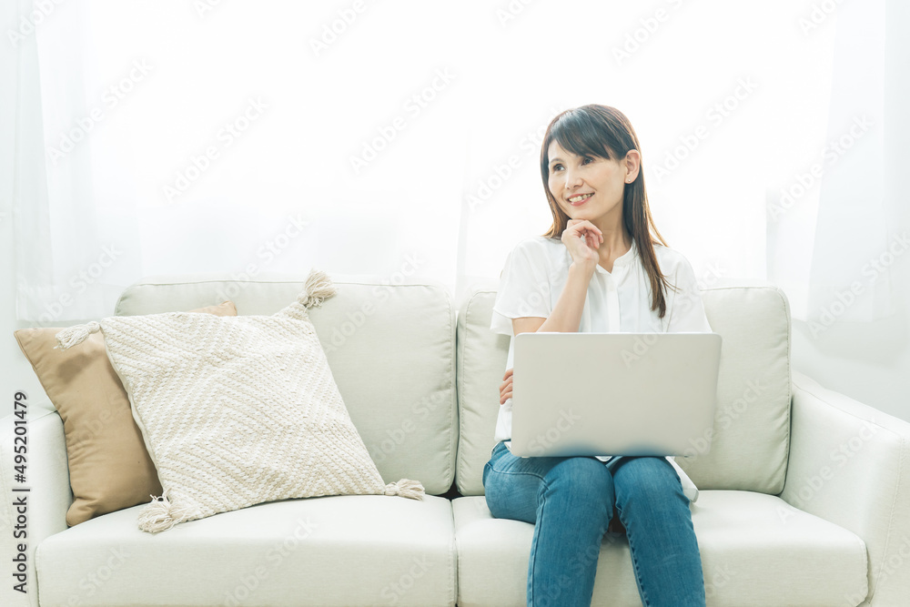 ソファに座る中高年女性(パソコン)
ソファに座る中高年女性(パソコン)