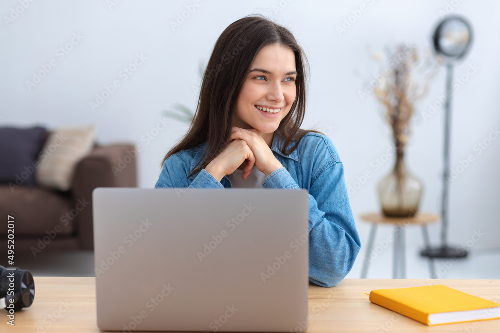 Online learning. Portrait of successful young caucasian woman using laptop while working remotely at home, distance education. Looking away and smiles friendly Online learning. Portrait of successful young caucasian woman using laptop while working remotely at home, distance education. Looking away and smiles friendly