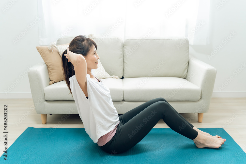 部屋で腹筋をするミドル世代の女性
部屋で腹筋をするミドル世代の女性