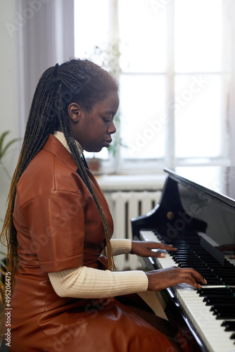 African young woman concentrating on her classical play on the grand piano in the class
