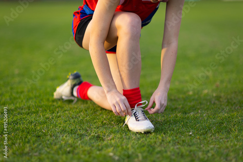 footballer wearing red socks kneeling down to tie bootlace