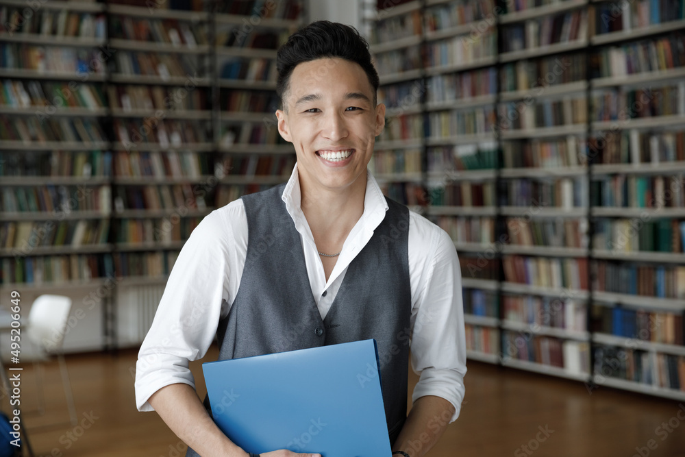 Happy attractive Korean guy student posing in university or public library, smile look at camera. Excellent studies, knowledge and education getting, successful higher institution admission concept Happy attractive Korean guy student posing in university or public library, smile look at camera. Excellent studies, knowledge and education getting, successful higher institution admission concept