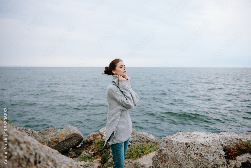 pretty woman in a gray sweater stands on a rocky shore nature female relaxing
