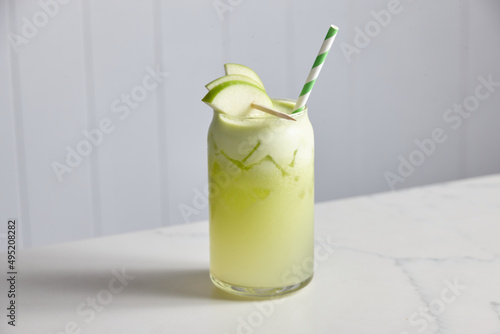 Glass of fresh apple juice with apple pieces and straw photo