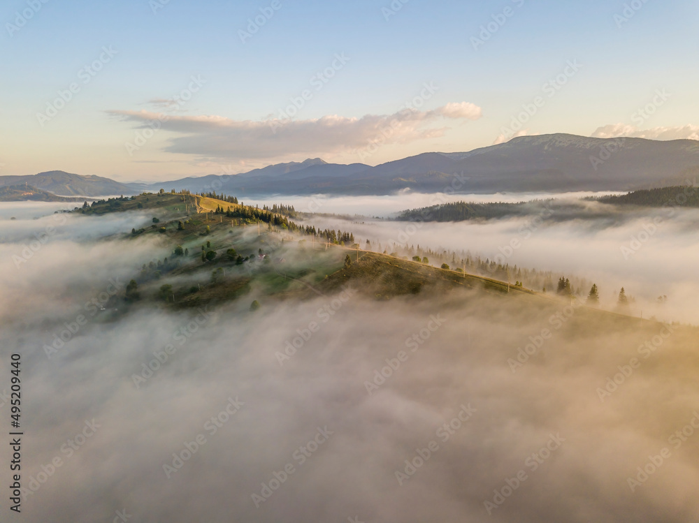 Mountain settlement in the Ukrainian Carpathians in the morning mist. Aerial drone view.