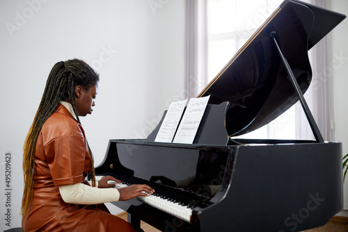 Wallpaper Mural African female pianist concentrating on her play on the grand piano, she studyin