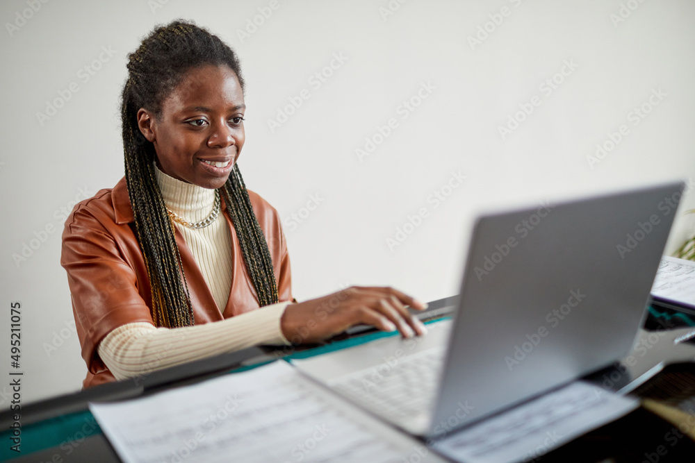African woman looking at monitor and smiling, she using laptop for learning the play on piano online African woman looking at monitor and smiling, she using laptop for learning the play on piano online