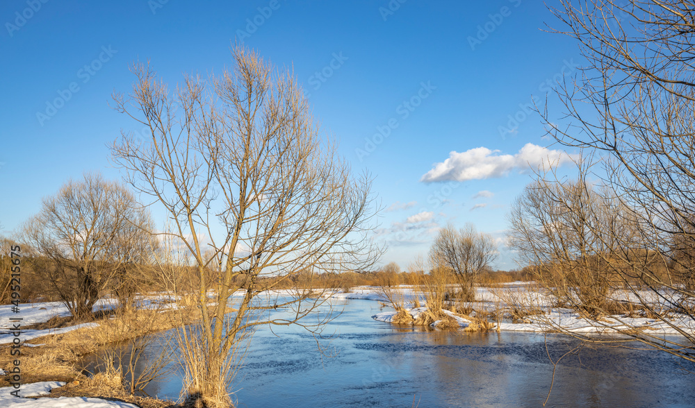 March sunny day by the river. A picturesque landscape, early spring, a river with snow-covered banks. The first thaws, the snow is melting. March sunny day by the river. A picturesque landscape, early spring, a river with snow-covered banks. The first thaws, the snow is melting.