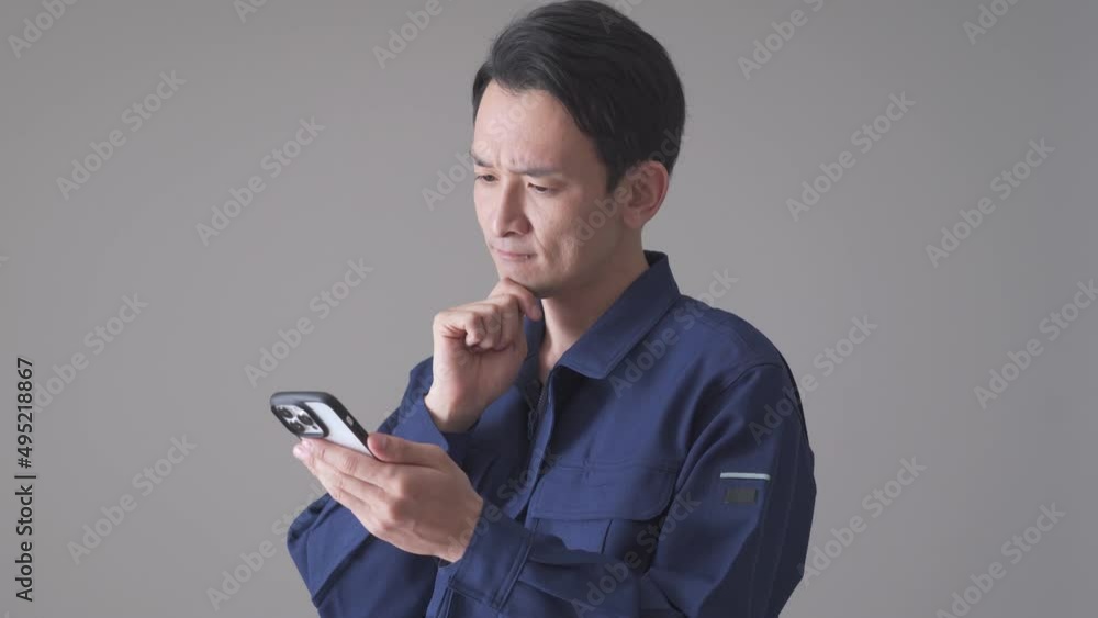 携帯を持ち悩む日本人男性 携帯を持ち悩む日本人男性