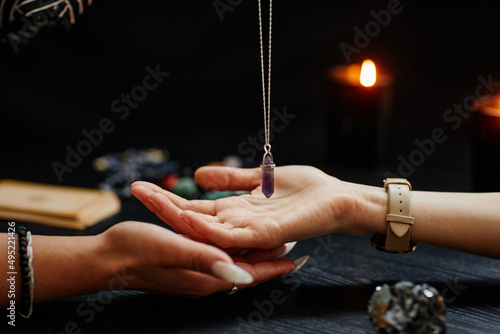 Side view closeup of fortune teller holding magic crystal over palm of young woman and reading her destiny in spiritual seance photo