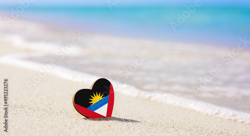 Flag of Antigua and Barbuda in the shape of a heart on a sandy beach. The concept of the best vacation in Antigua and Barbuda photo