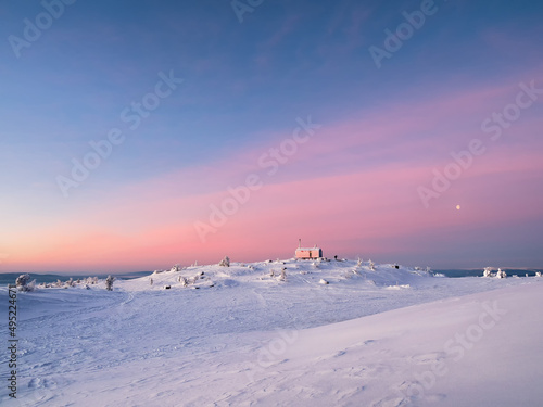Cabin in winter. Dubldom on the mountain Volodyanaya Kandalaksha, Murmansk region in Russia. Holidays, vacations in winter. Beautiful Arctic sunset. Scenic colorful sky at dawn. Winter time. photo