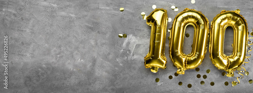 Yellow foil balloon number, number one hundred on a concrete background. Greeting card with the inscription 100. Anniversary concept. for anniversary, birthday, new year celebration. banner, photo