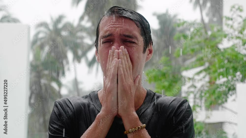 Portrait of crying sad man standing in the pouring rain and getting soaked. Slow motion shot Portrait of crying sad man standing in the pouring rain and getting soaked. Slow motion shot