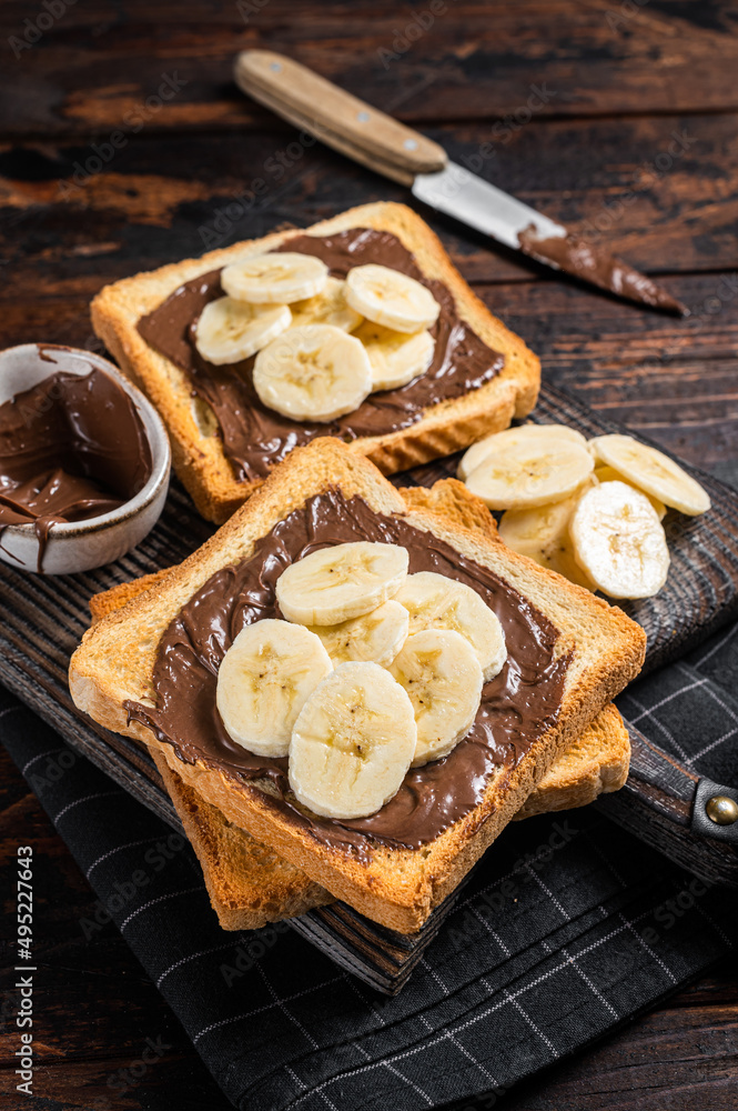 Toasts bread with bananas and chocolate cream on wooden board. Wooden background. Top view