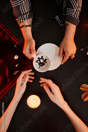 Top down view at female fortune teller reading coffee grounds telling destiny in seance with young woman photo