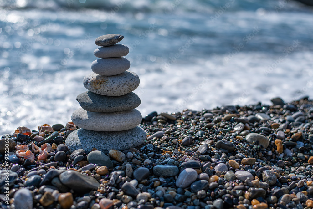 pyramid of stones balances on a pebble beach on a blurred background of the sea. concept meditation yoga zen