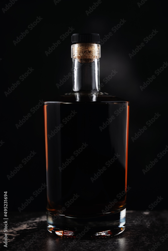 Full glass brandy bottle on dark background