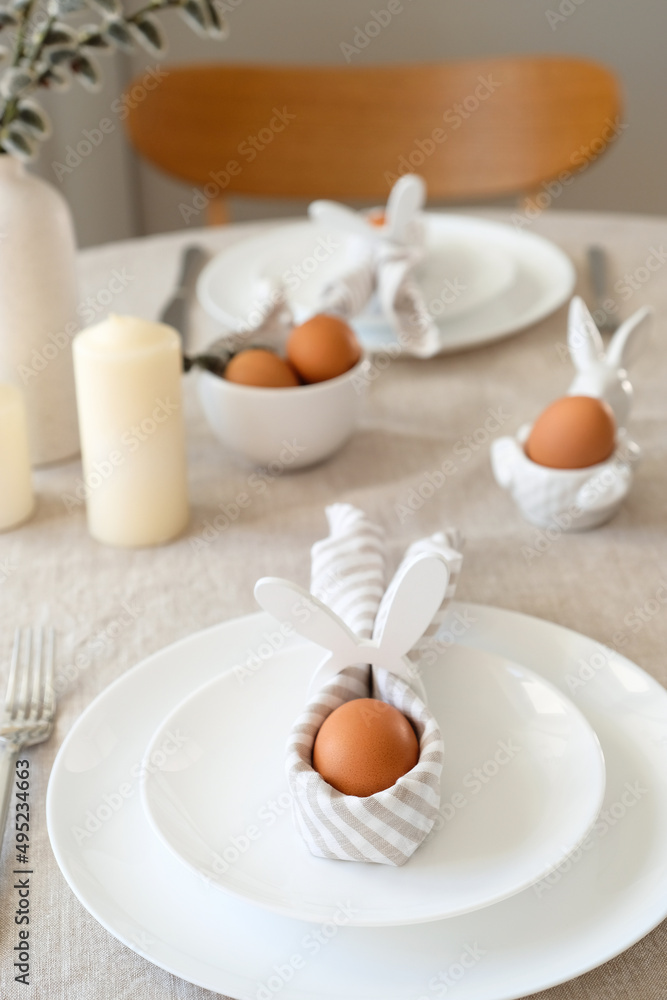 Easter table setting with egg in Easter bunny napkin on plate. Easter table serving. Easter table setting with egg in Easter bunny napkin on plate. Easter table serving.
