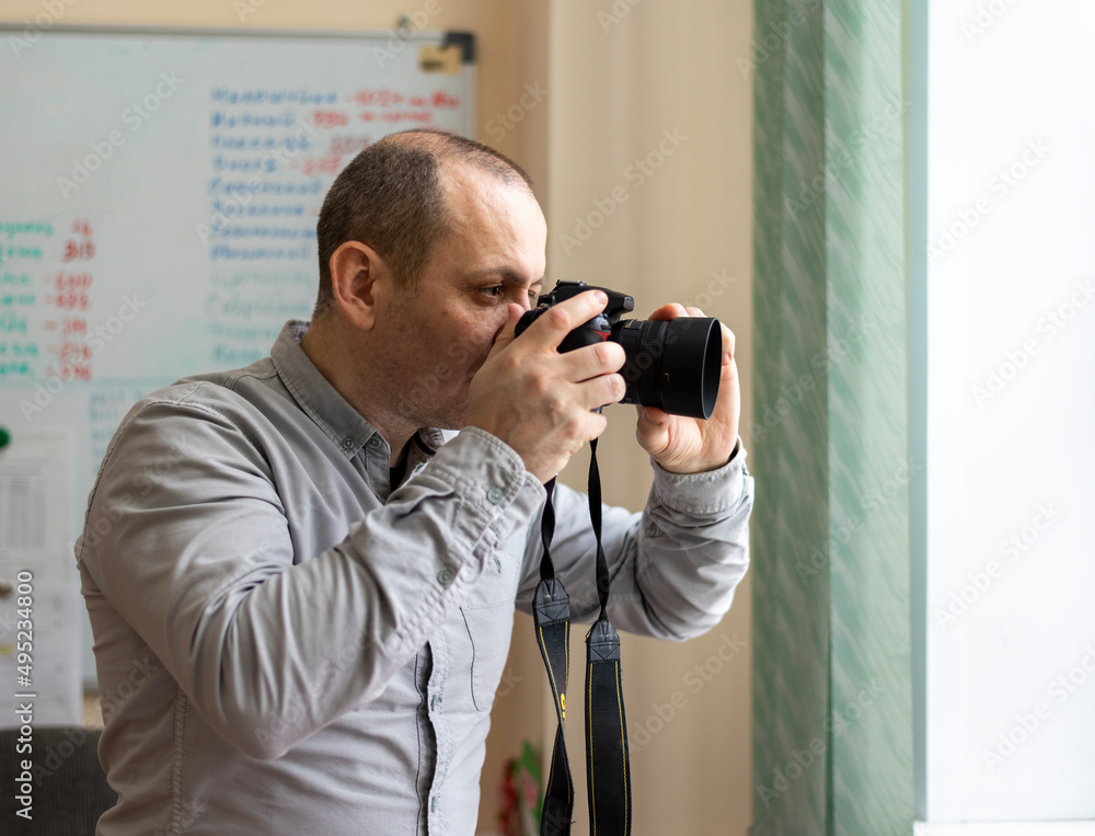 A photojournalist With A Camera In His Hands Takes Pictures Through the window A photojournalist With A Camera In His Hands Takes Pictures Through the window