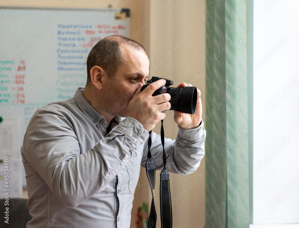 A photojournalist With A Camera In His Hands Takes Pictures Through the window