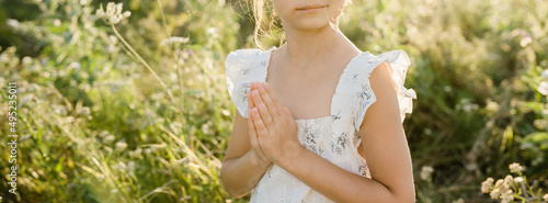 Praying hands of little girl. Praying for freedom. Photo in the fields. Hands folded in prayer. Religion and meditation concept
