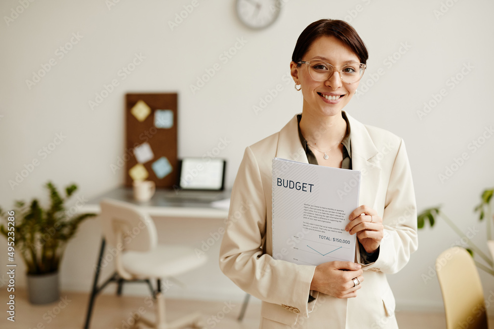 Waist up portrait of successful young businesswoman looking at camera in minimal office, copy space Waist up portrait of successful young businesswoman looking at camera in minimal office, copy space