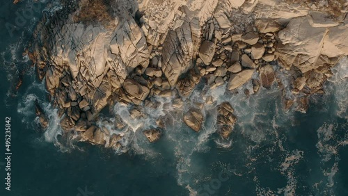 Aerial top down view of rocky coastline. sunset light and big waves