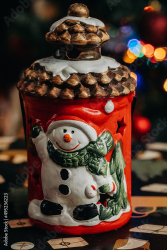Christmas lantern with a snowman figurine against the background of multi-colored Christmas tree lights. Christmas decorations. bokeh. Christmas and New Year