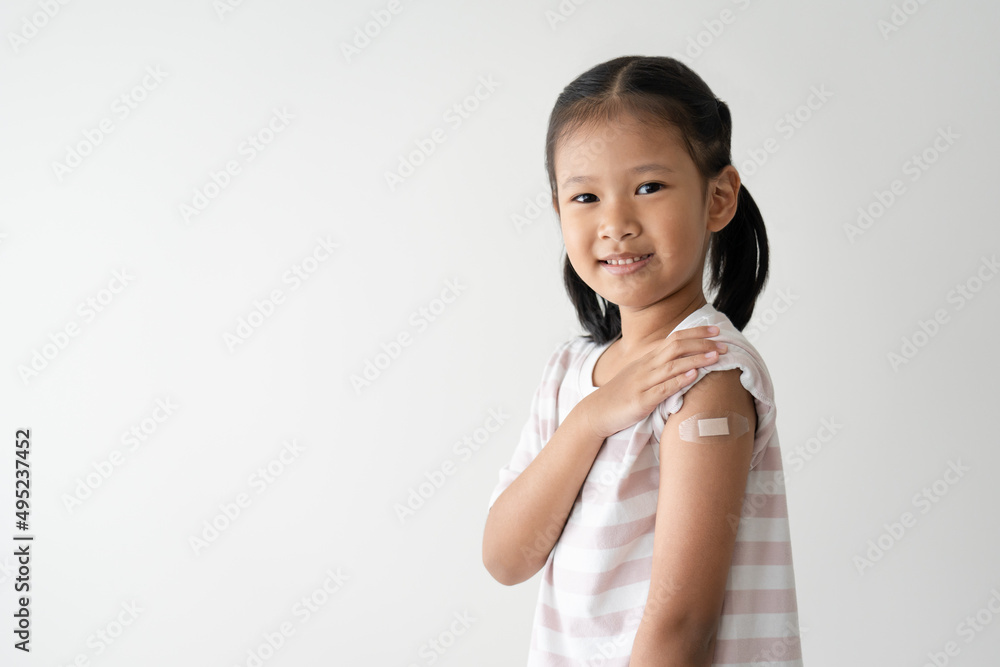 Asian little girl showing her arm with plaster after virus vaccine. Kid and child vaccination campaign Asian little girl showing her arm with plaster after virus vaccine. Kid and child vaccination campaign