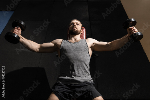 man doing arm raises with dumbbells in the gym © Artem