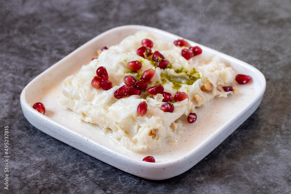 Gullac dessert on dark background. Traditional Ramadan dessert. Güllaç dessert decorated with pistachio and pomegranate. Turkish cuisine delicacies. Close up
