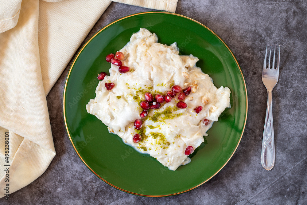 Gullac dessert on dark background. Traditional Ramadan dessert. Güllaç dessert decorated with pistachio and pomegranate. Turkish cuisine delicacies. Top view Gullac dessert on dark background. Traditional Ramadan dessert. Güllaç dessert decorated with pistachio and pomegranate. Turkish cuisine delicacies. Top view