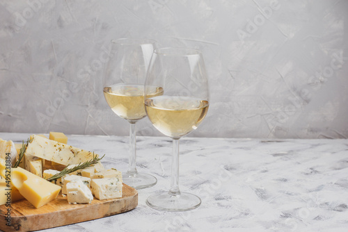 Cheese and a glass of white wine on a grey background. Different cheeses on a wooden board. Cheese set. Empty tablecloth for product montage. Free space for your text © Martinesku