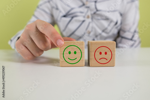 Hand of a businessman chooses a smiley face on wood block cube, The best excellent business services rating customer experience,