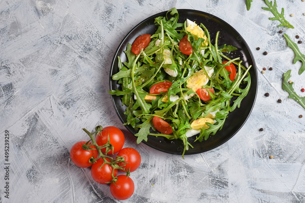 Salad with cherry tomatoes, fresh arugula and quail egg. Concept for a tasty and healthy meal. Vitamins in vegetables and herbs for immunity against the virus. Top view. Copy space