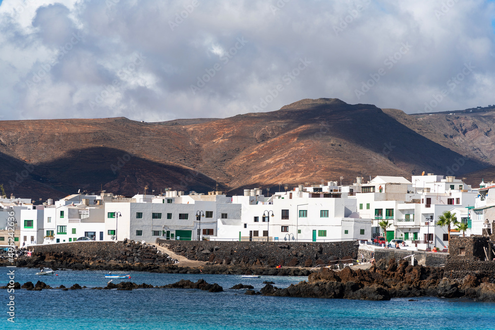 costa de Lanzarote en las islas canarias con un mar en calma color turquesa y casas blancas típicas una montaña volcánica en la parte trasera. turismo en España. vacaciones de relax
