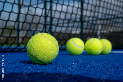selective focus, four paddle tennis balls and the net of a blue paddle tennis court
