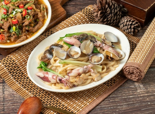 fried noodles with clam rolls in a dish isolated on mat side view on dark wooden table taiwan food