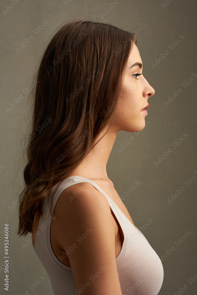 Profiling beauty. Studio profile of an attractive young woman standing against a brown background. Profiling beauty. Studio profile of an attractive young woman standing against a brown background.