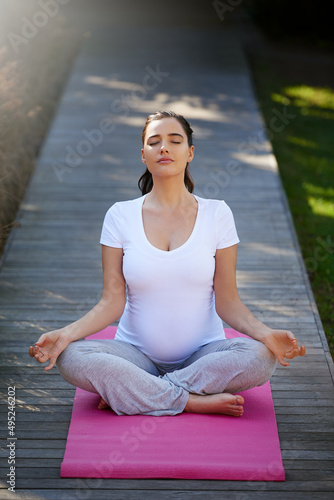 Just keep calm.... Shot of a young pregnant woman doing yoga outside. © C Mcdonald/peopleimages.com