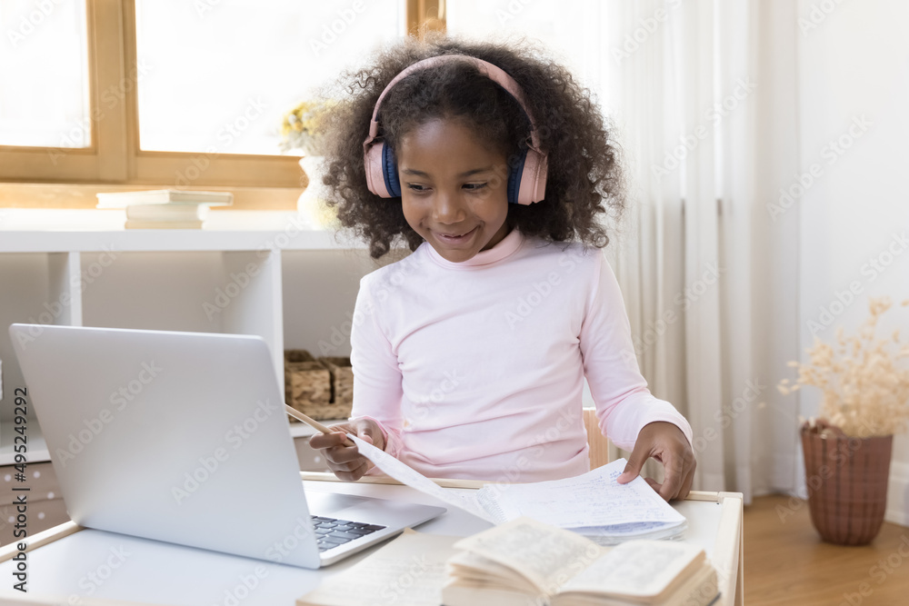 Happy African gen Z school kid in trendy pink headphones studying ...