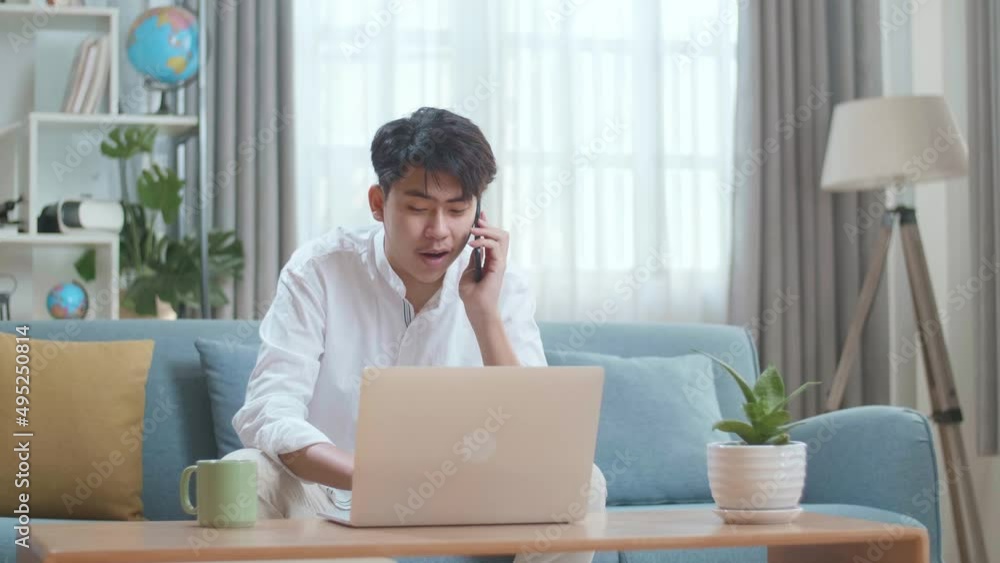 Smiling Asian Man Answering The Call On Smartphone While Using Laptop Computer In The Living Room
Smiling Asian Man Answering The Call On Smartphone While Using Laptop Computer In The Living Room